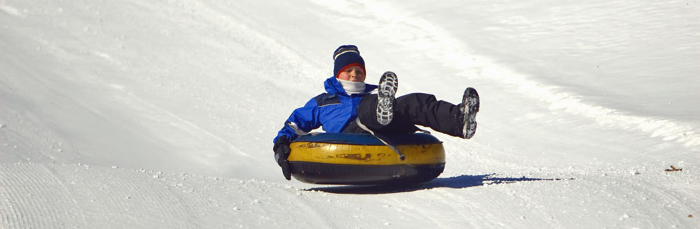 boy riding tube down snow hill, California